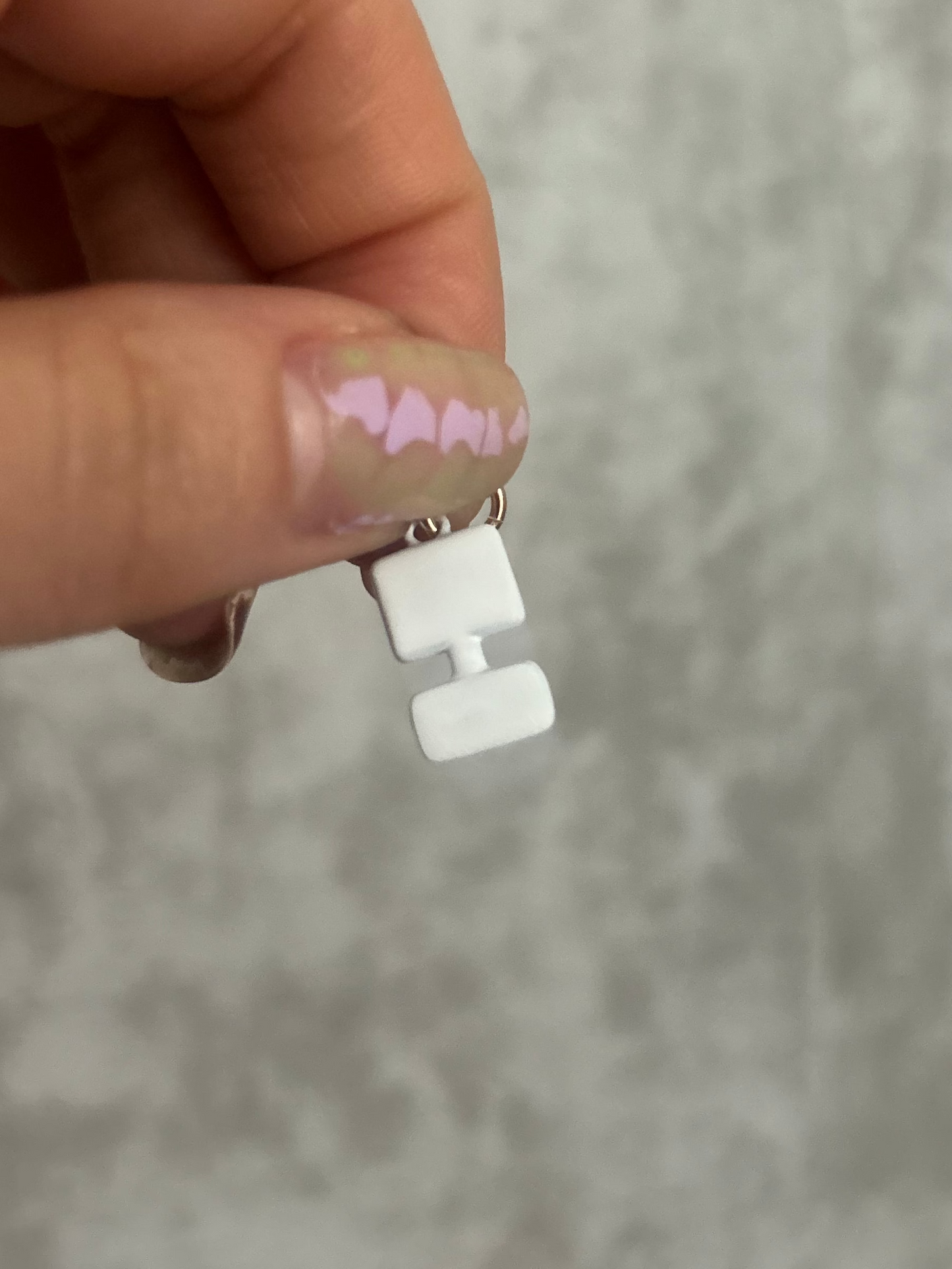 Hand holding a small white object with computer on a gray background