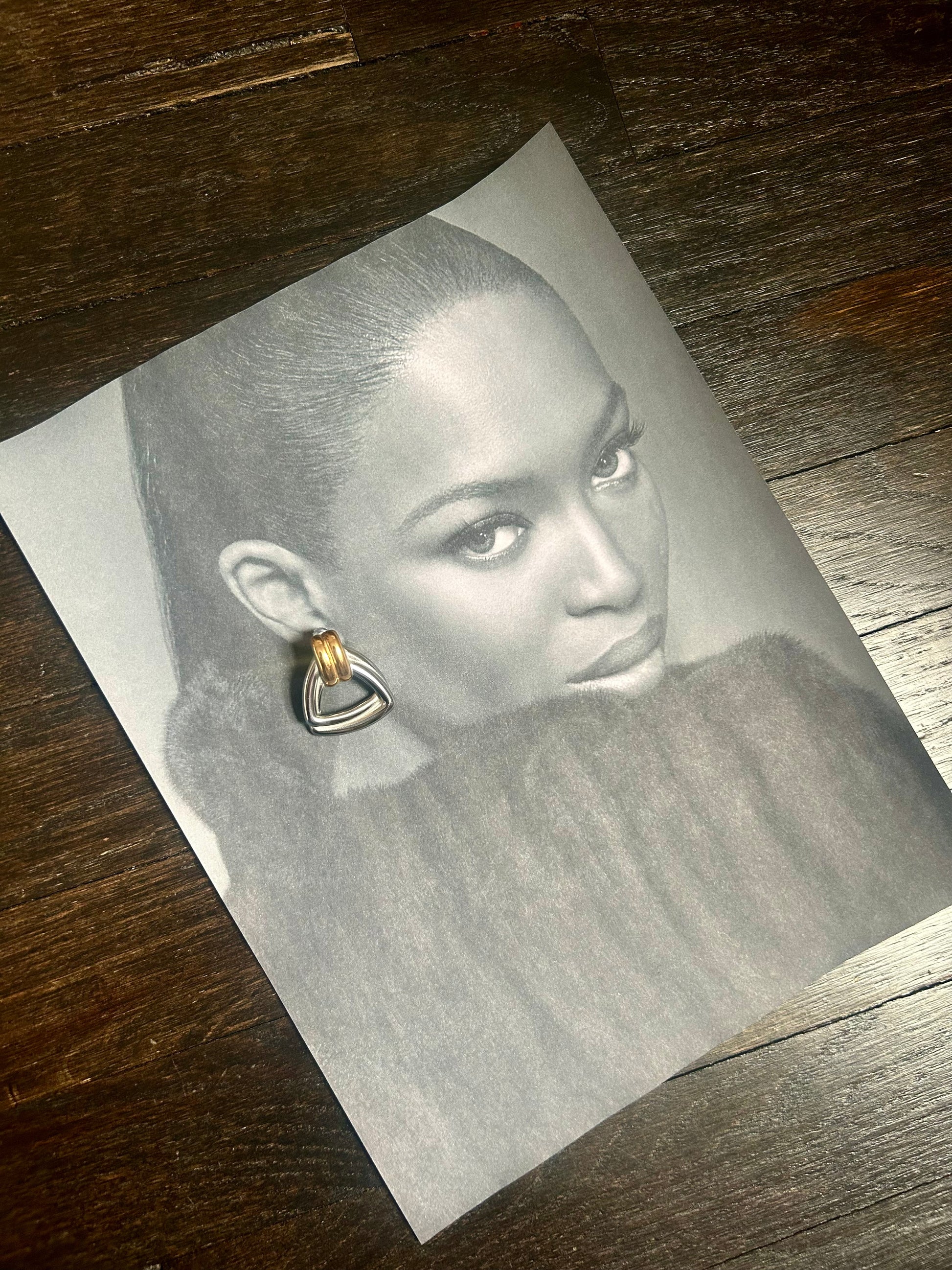 Model wearing vintage-inspired silver stud earrings with slick bun hairstyle