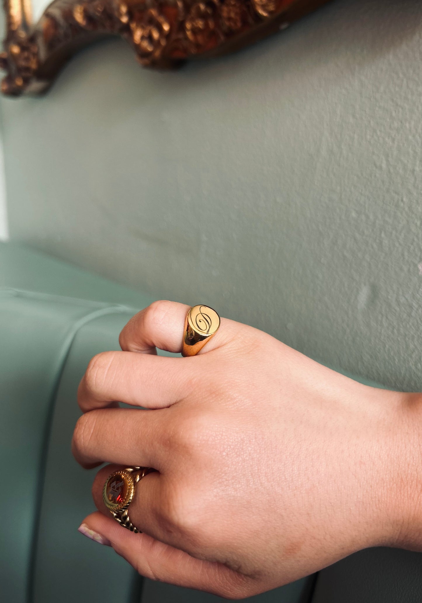 Hand wearing two gold rings with a plain background