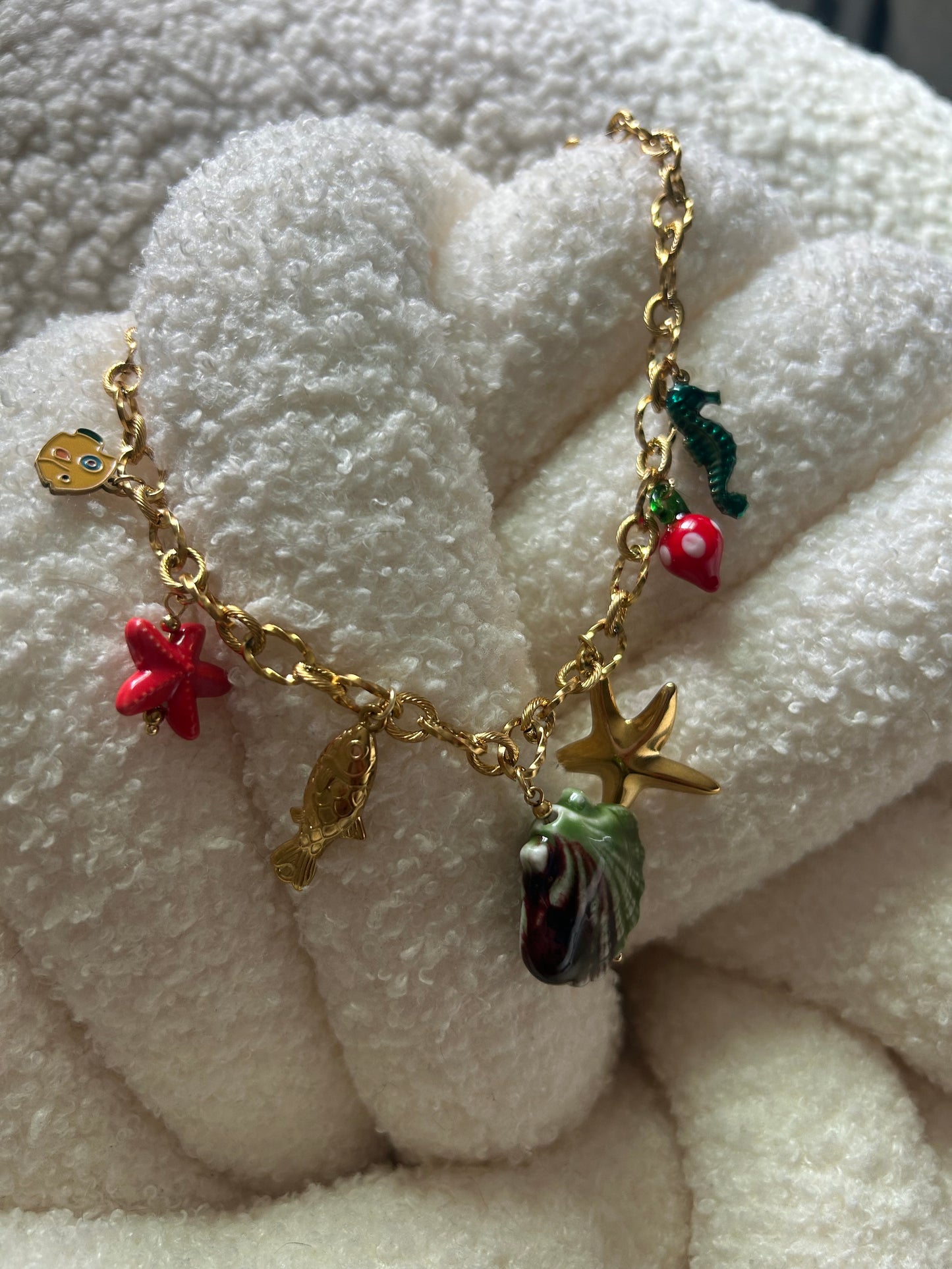 Gold bracelet with various charms on a white textured surface