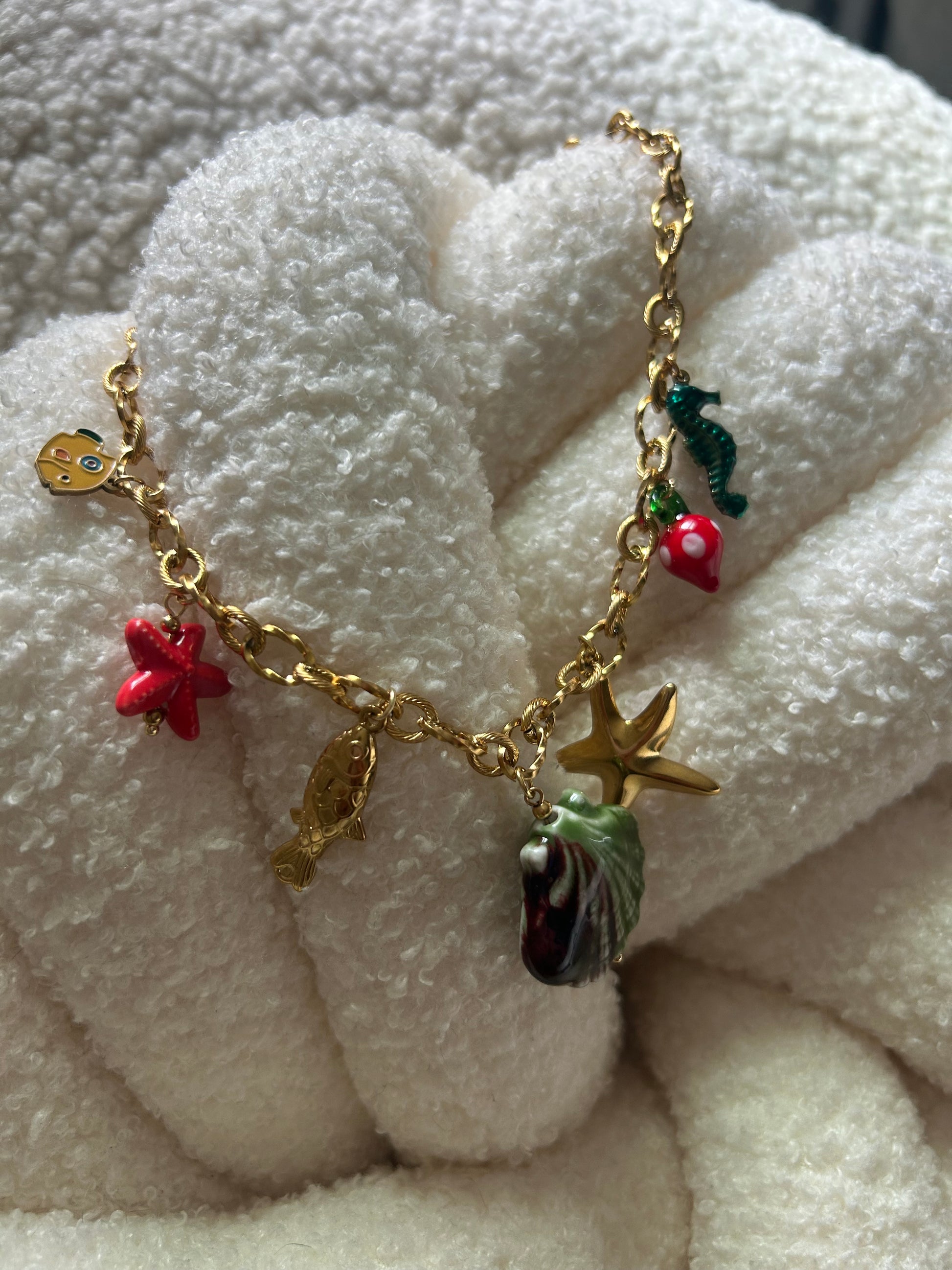 Gold bracelet with various charms on a white textured surface