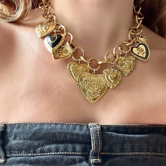 Gold necklace with heart-shaped pendants worn over a denim top