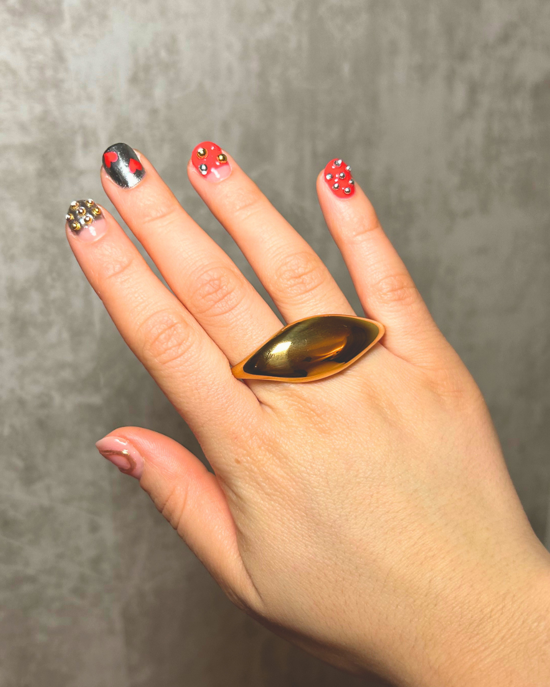Hand wearing a gold double finger ring a gray background