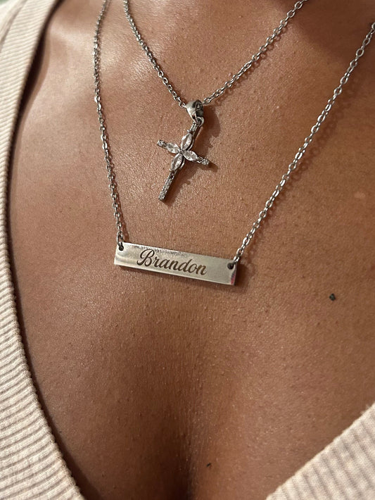 Necklace with a star pendant and bar pendant on a person wearing a beige sweater.