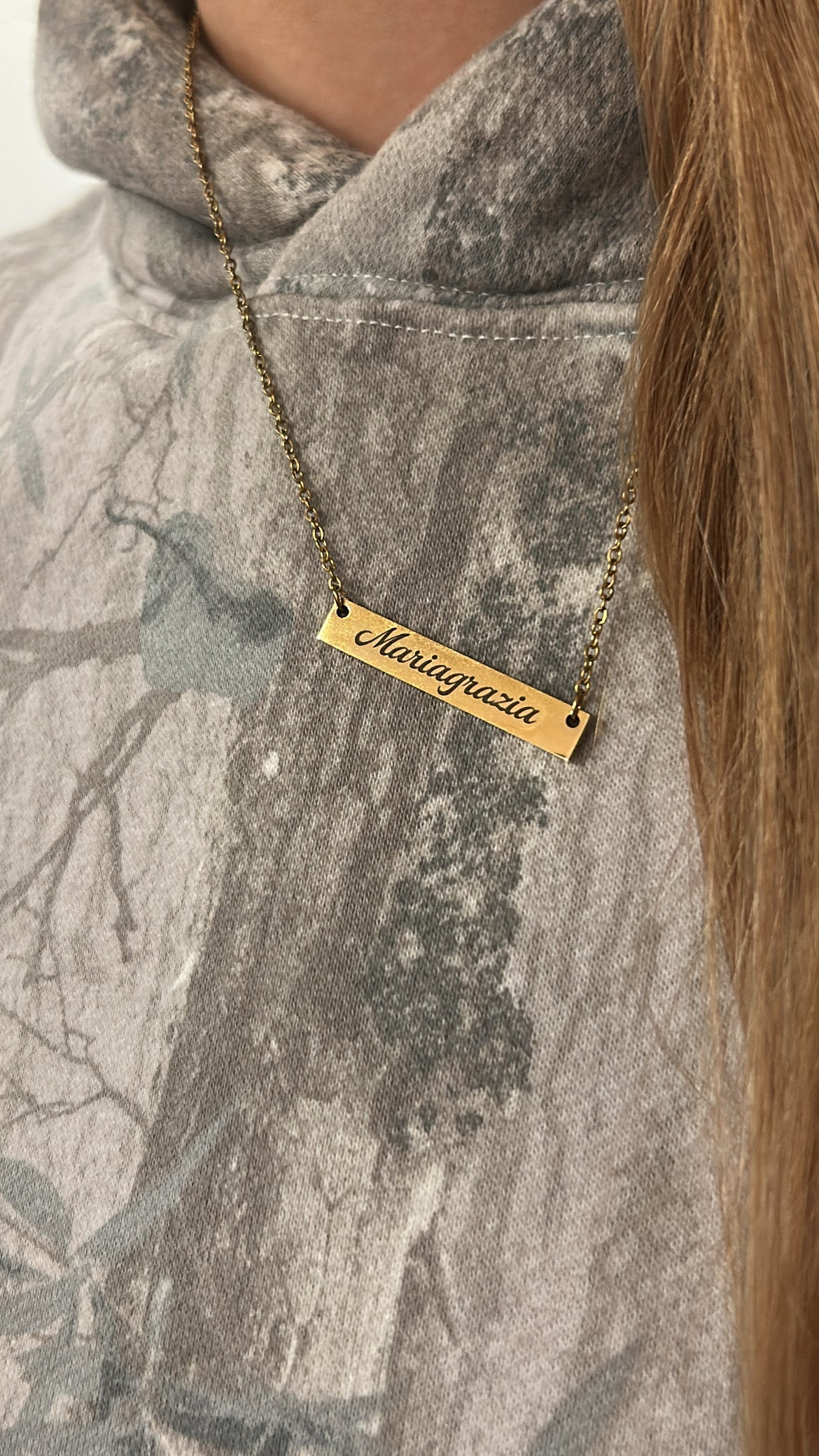 Gold necklace with engraved name on a camouflage jacket