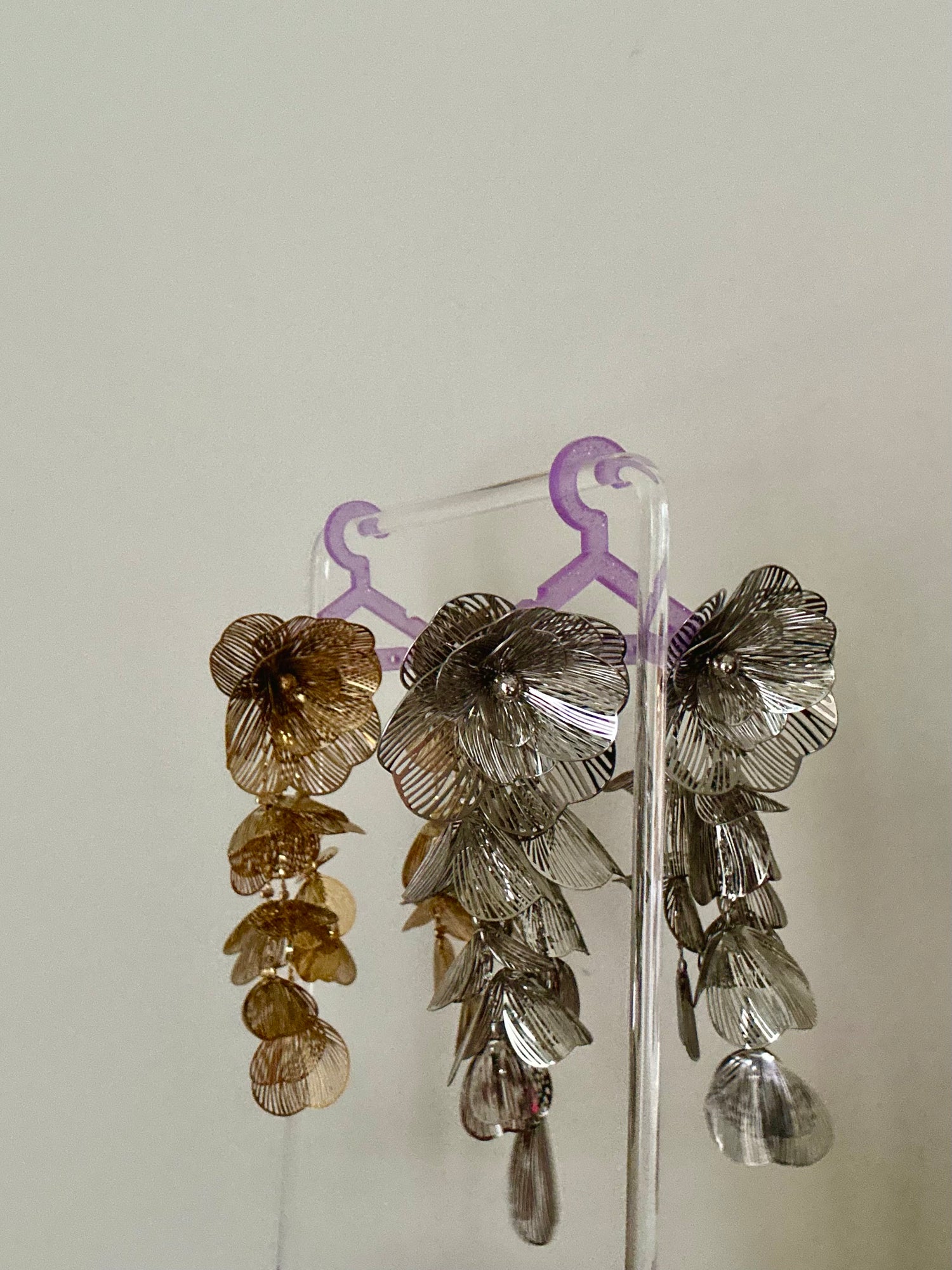 Pair of floral earrings on a clear stand against a plain background
