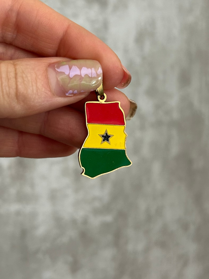 Hand holding a small pendant with a colorful design against a neutral background