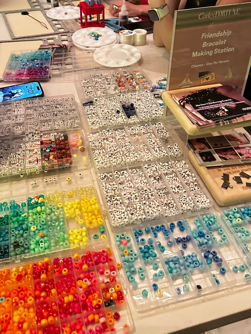 Two women looking at a display of colorful beads and jewelry on a table.