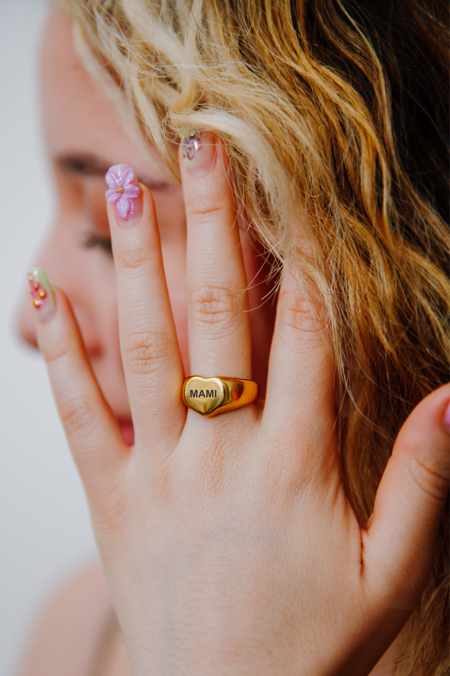 Woman with manicured nails wearing engraved heart-shaped mom ring – Mother’s Day gift jewelry