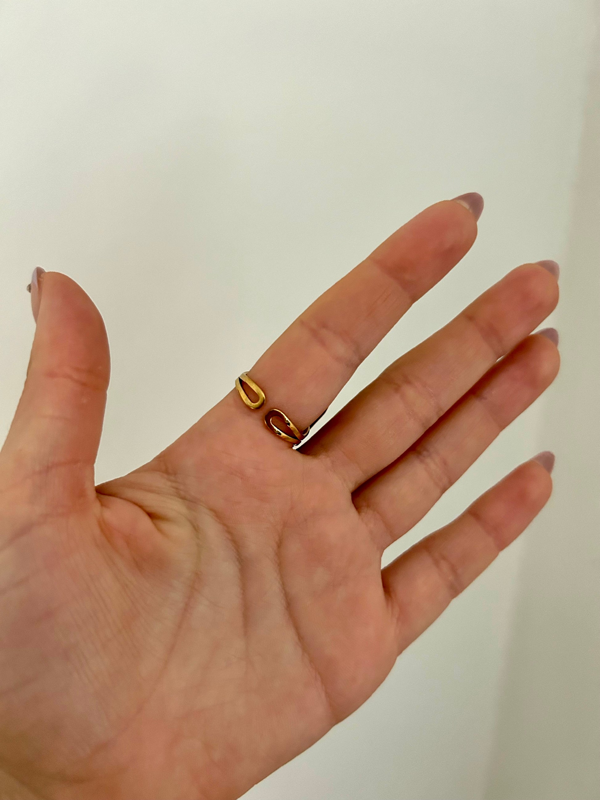 Hand wearing a gold ring on a plain background
