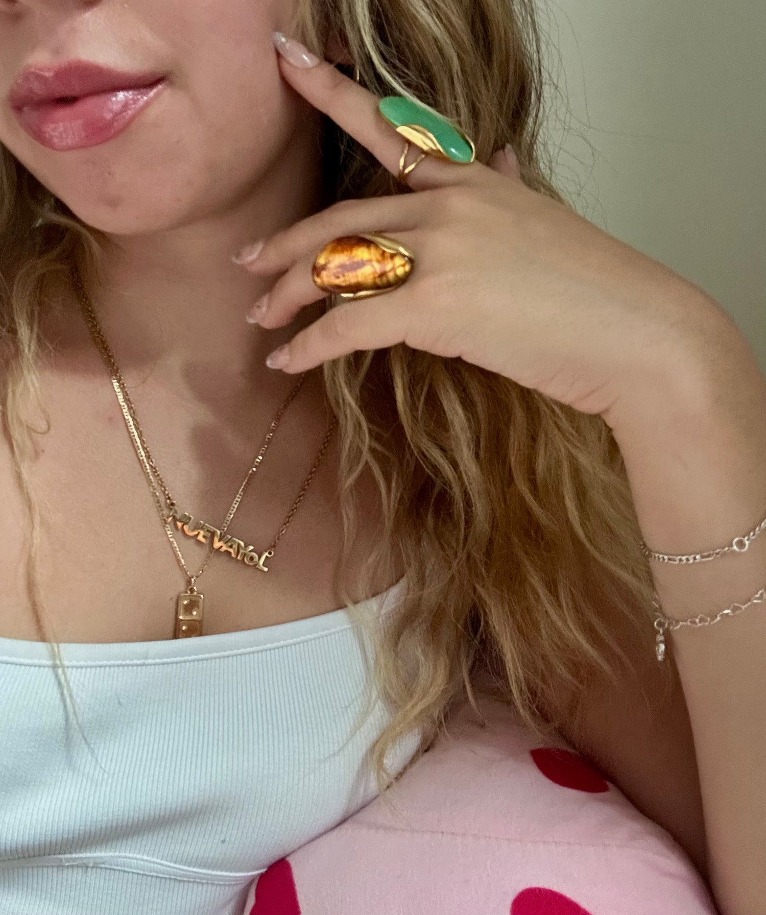 Close-up of a person wearing gold jewelry including a necklace, ring, and bracelet.