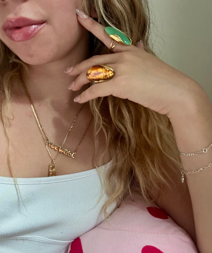 Close-up of a person wearing gold jewelry including a necklace, ring, and bracelet.
