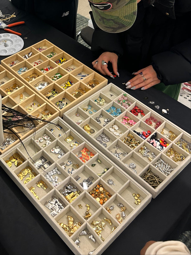 Two people looking at a collection of small items in compartments on a table.