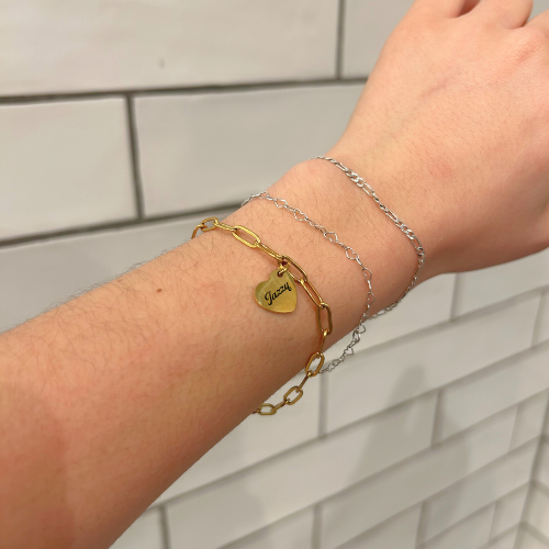 Hand wearing multiple bracelets with a neutral background