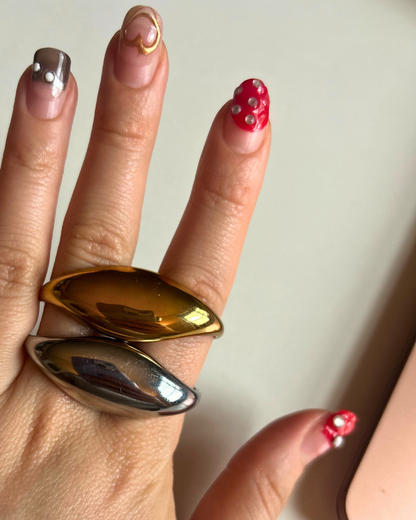 Gold and silver ring on a finger with a plain background