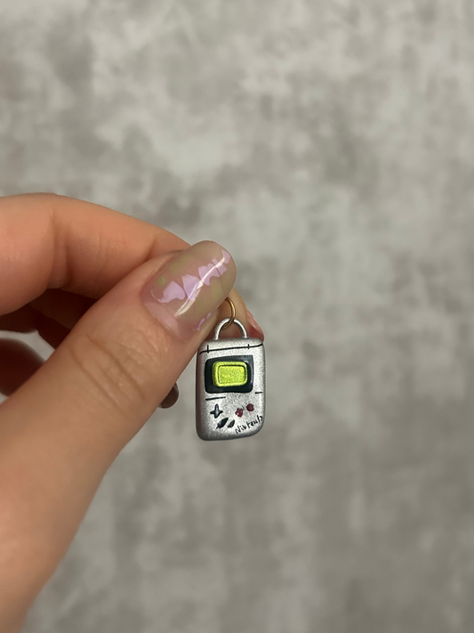 Small Nintendo charm held between fingers against a neutral background