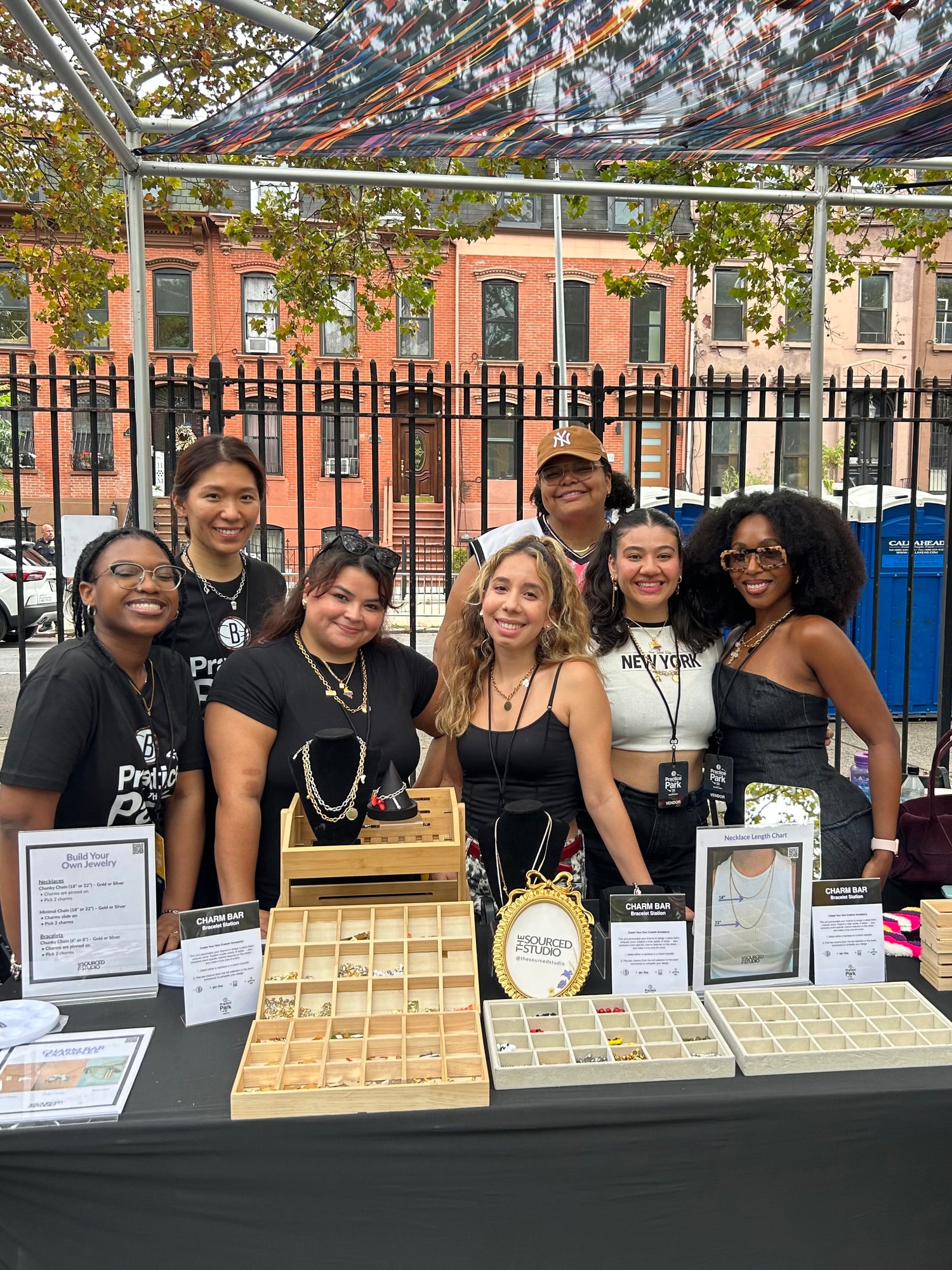 Group of women standing behind a table with jewelry at an outdoor event for the Brooklyn Nets. 