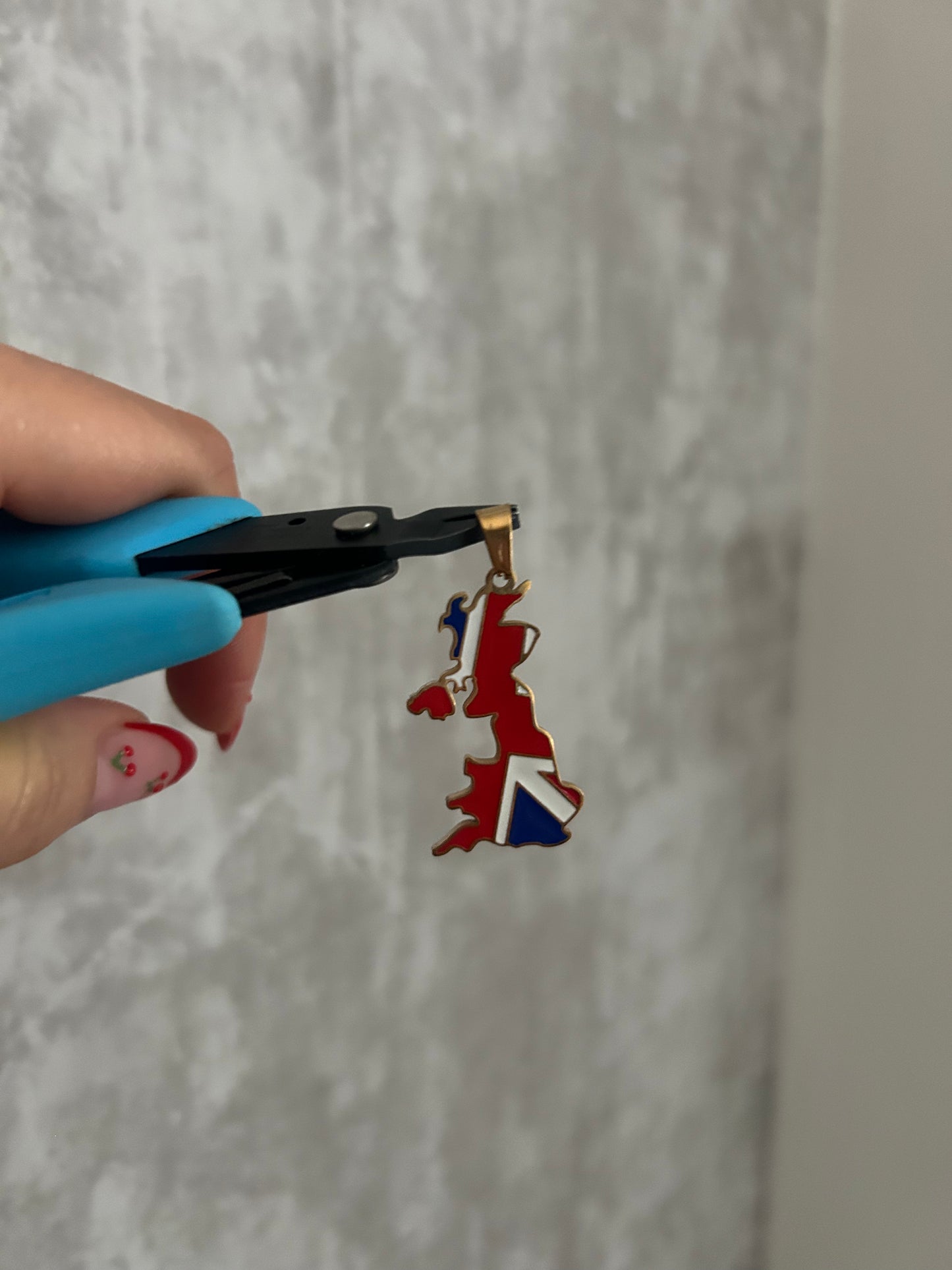 United Kingdom Flag necklace being held by pliers