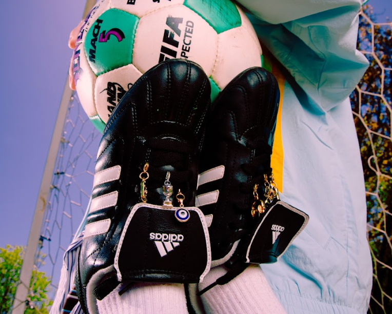 Person holding a soccer ball and gloves with a goalpost in the background