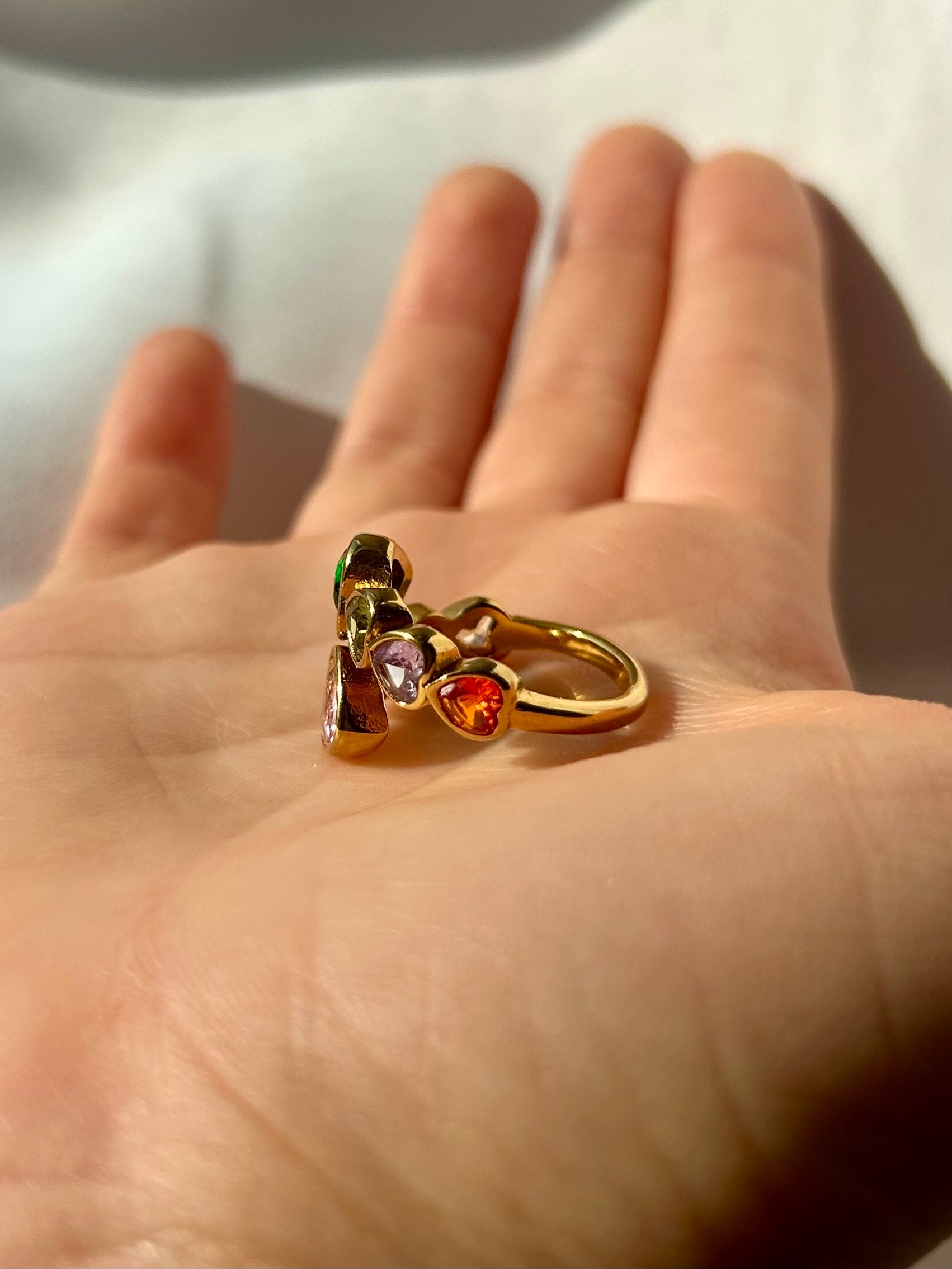 Flat lay of Arcoíris ring on neutral fabric background – statement heart ring