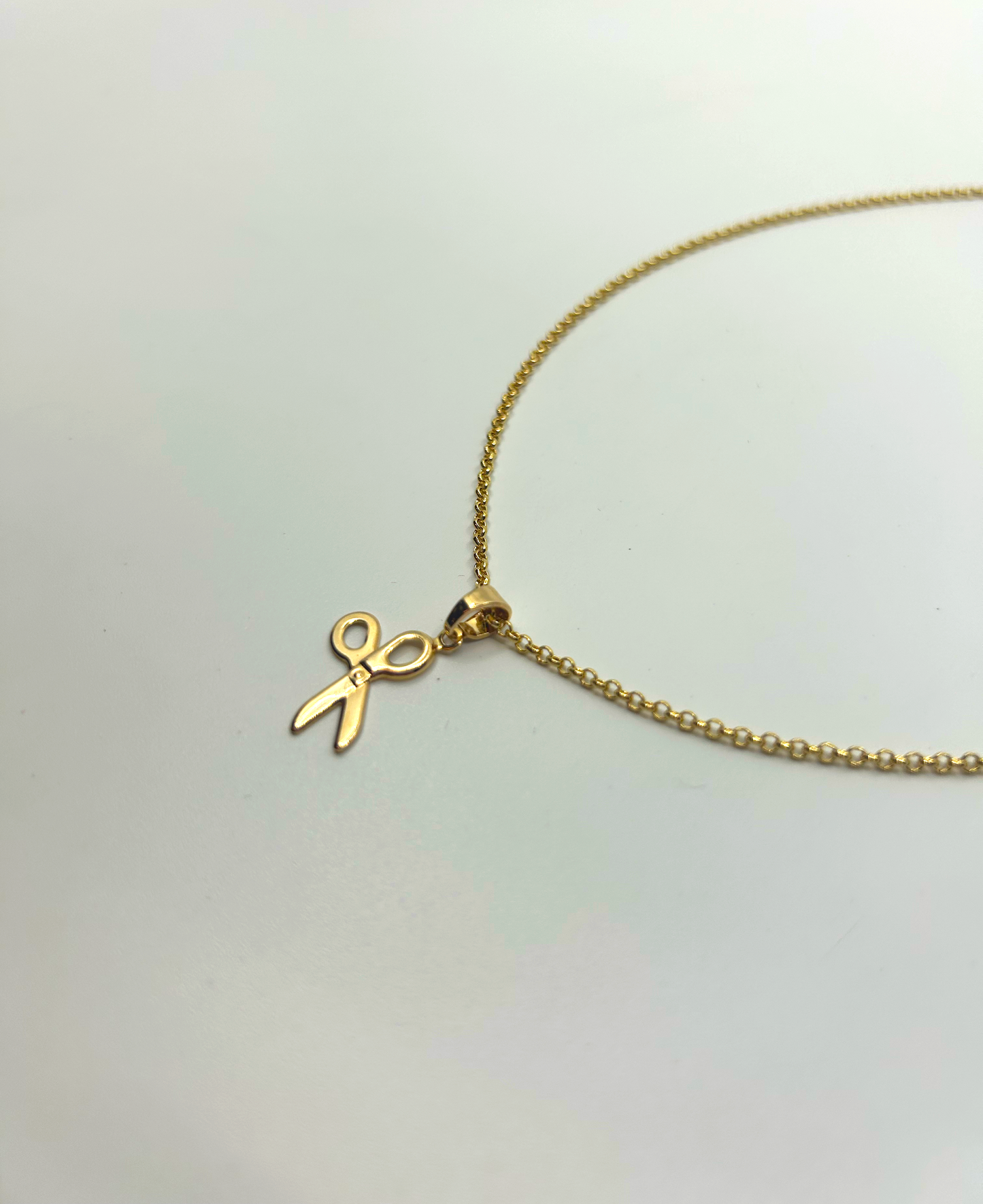 Layered necklace stack featuring gold scissor pendant