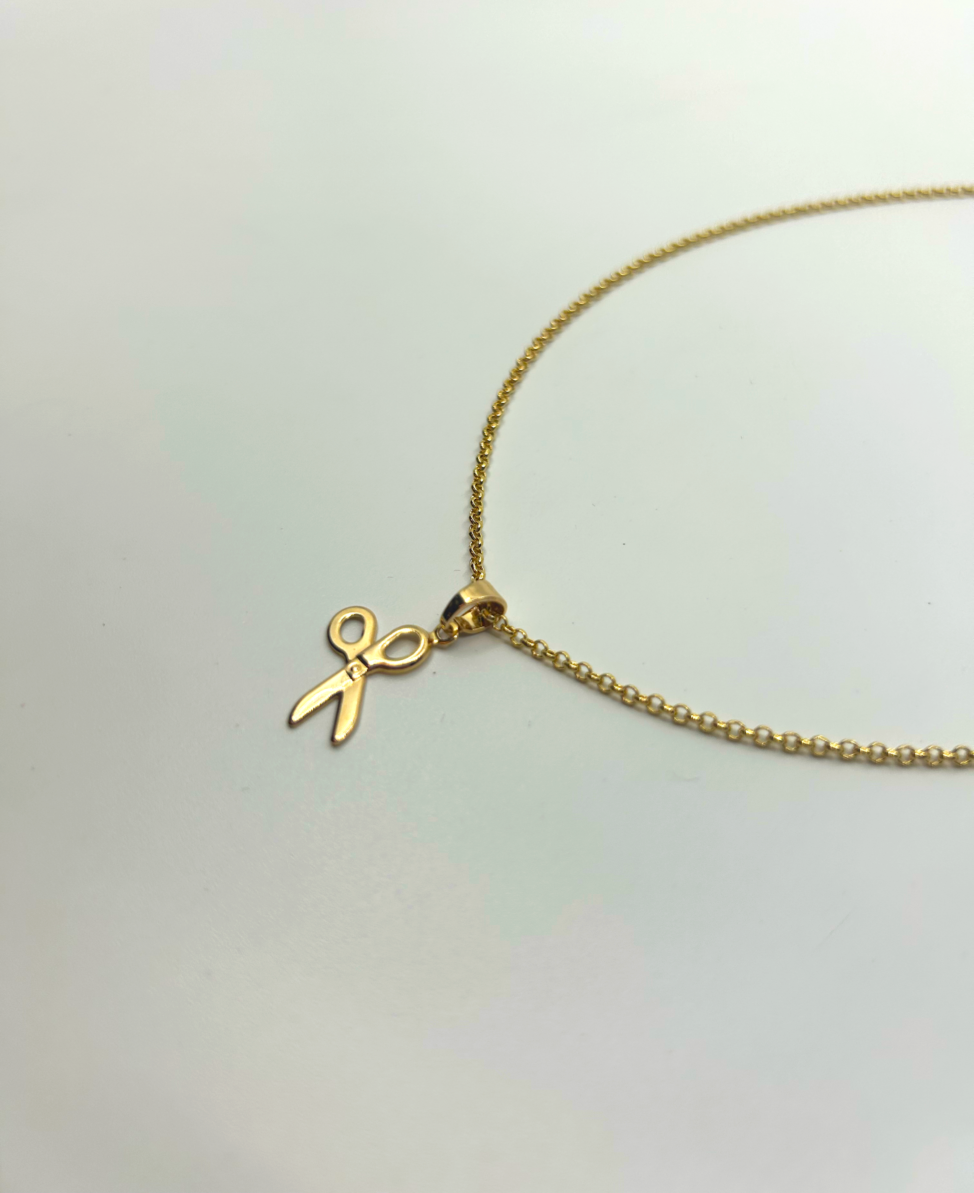 Layered necklace stack featuring gold scissor pendant