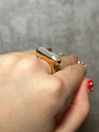 Close-up of a hand wearing a gold ring on a gray background