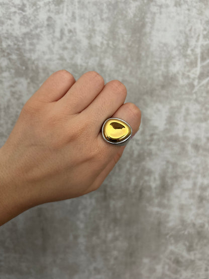 Hand wearing a gold ring on a gray background