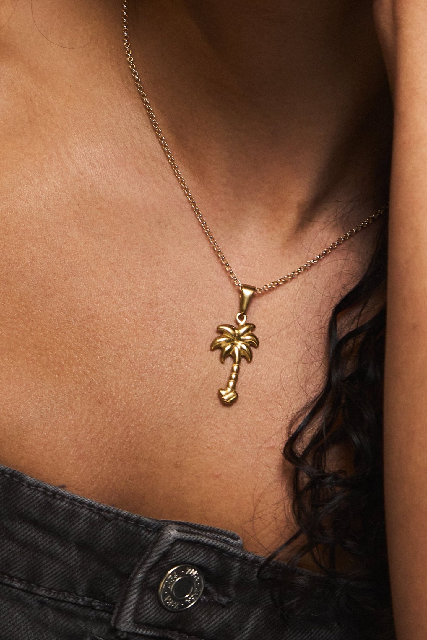 Close-up of dainty gold palm charm on link chain