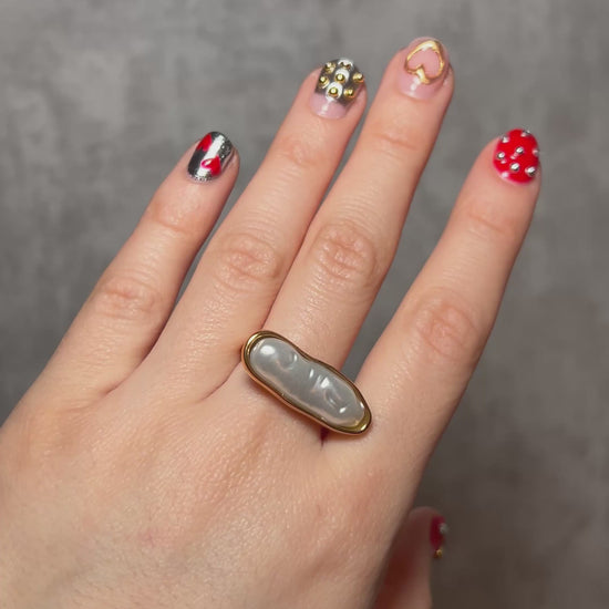 Gold stainless steel statement ring featuring an elongated pearl centerpiece in a sleek capsule-shaped setting