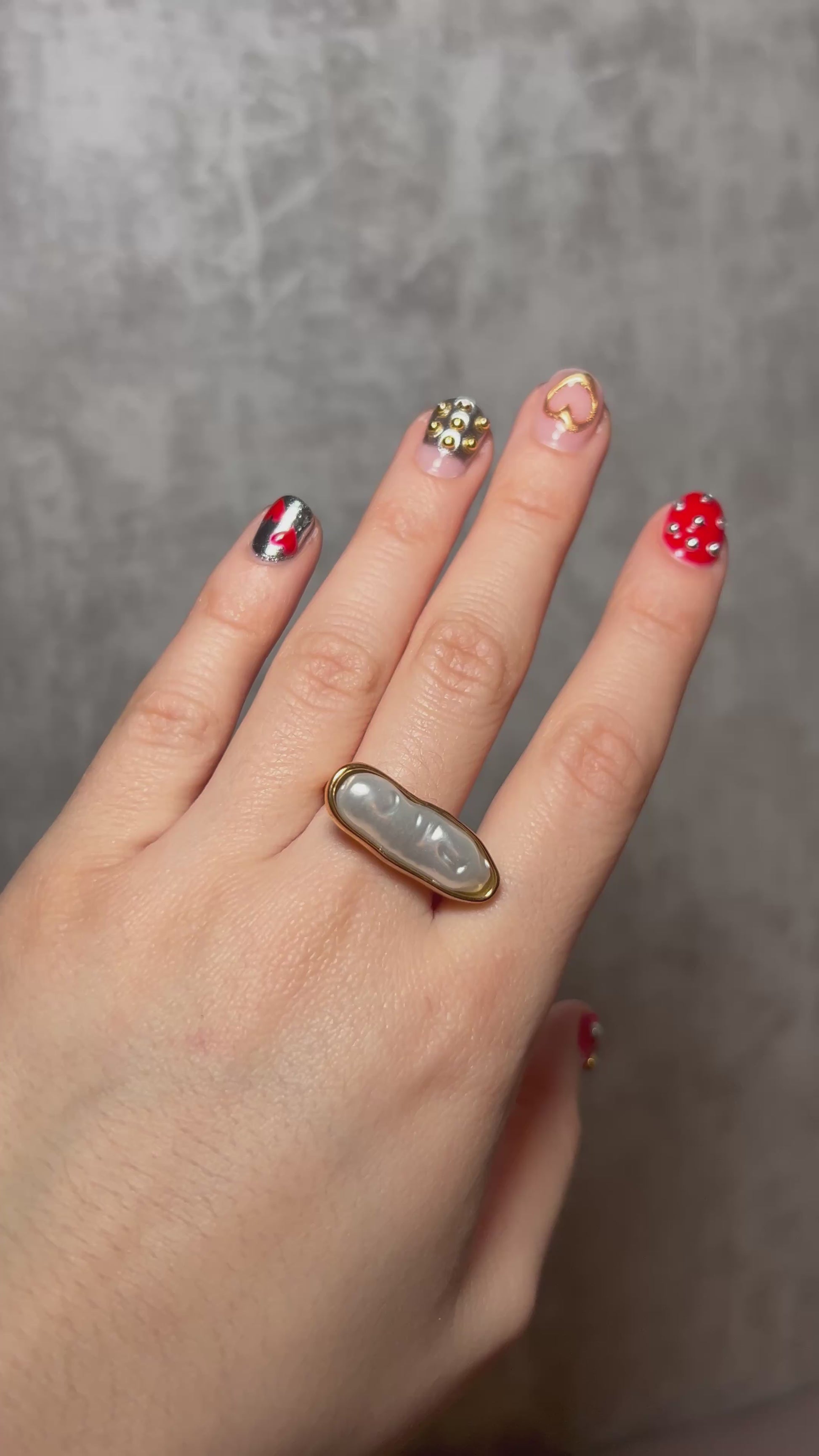 Gold stainless steel statement ring featuring an elongated pearl centerpiece in a sleek capsule-shaped setting
