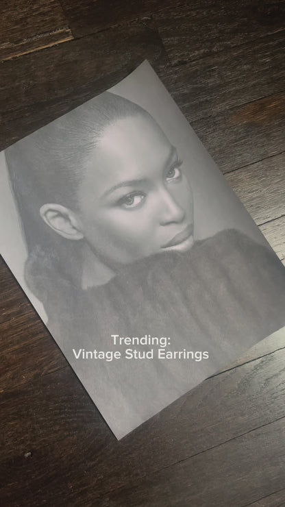 Model wearing vintage-inspired gold stud earrings with slick bun hairstyle