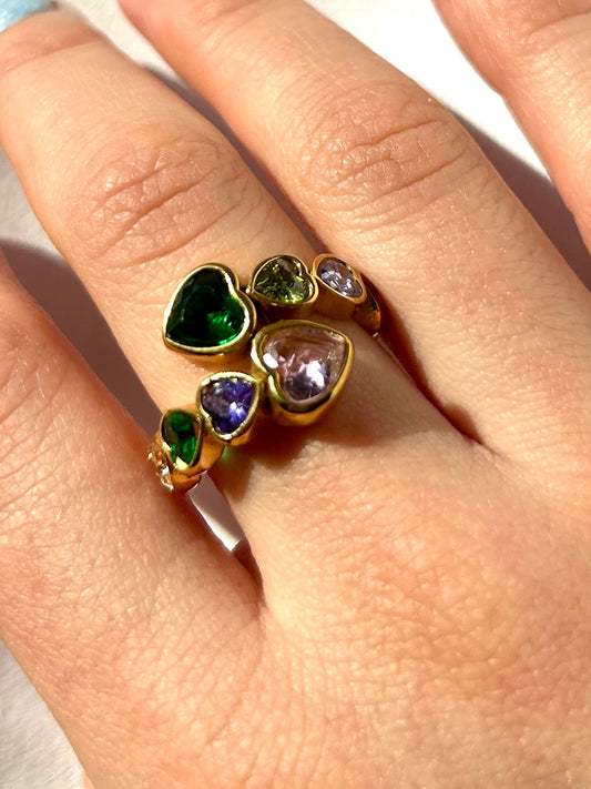 Model wearing gold adjustable rainbow heart ring on hand with natural nails