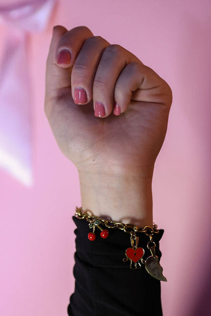 Hand with bracelets raised against a pink background