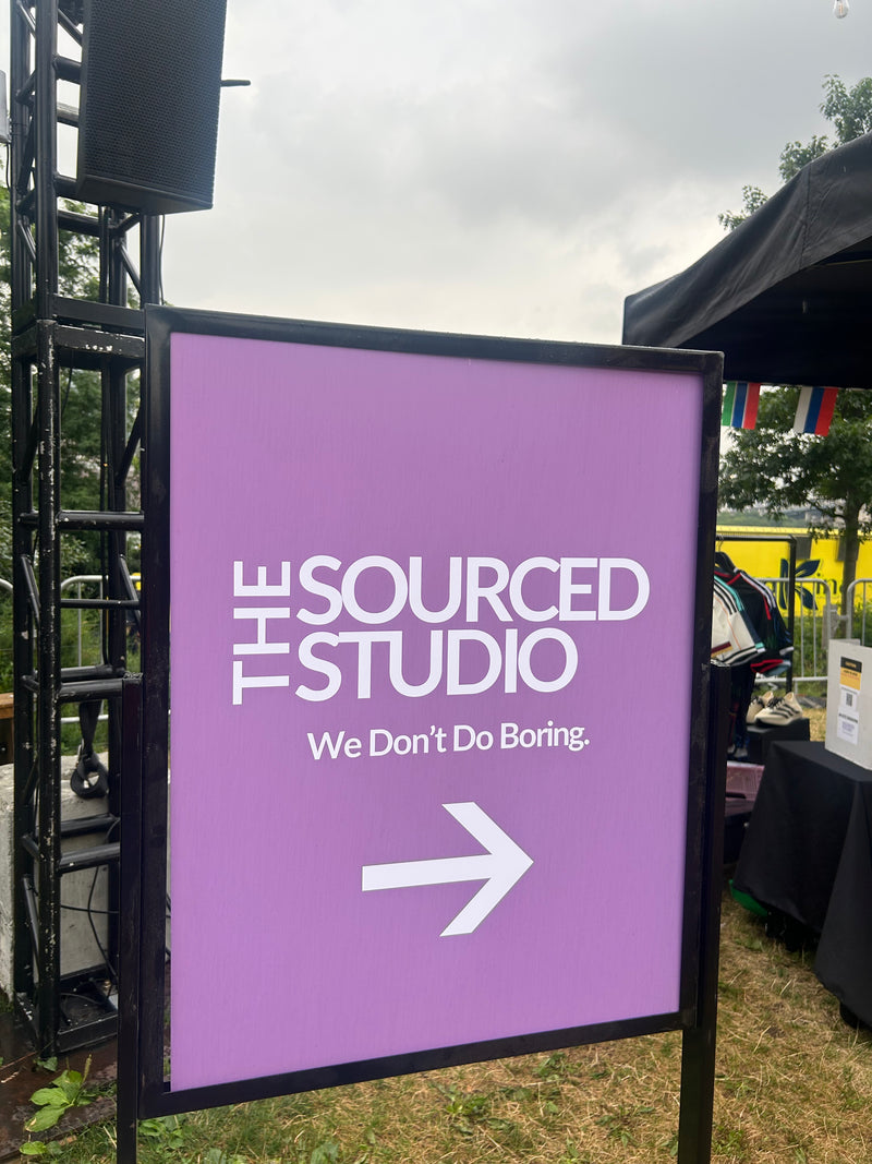 Purple sign pointing to 'The Sourced Studio' with an arrow on a grassy outdoor area.