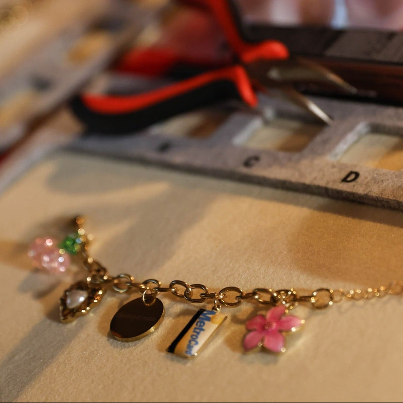 Gold bracelet with charms on a table with stationery items