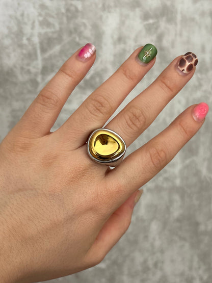 Hand wearing a ring with a yellow gemstone on a gray surface