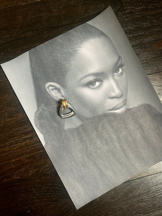 Model wearing vintage-inspired gold stud earrings with slick bun hairstyle